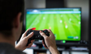 An image of a man playing football video games on a playstation